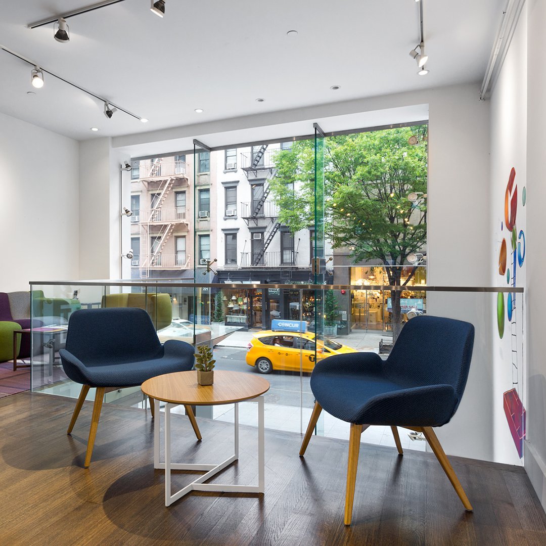 "Modern blue armchairs paired with a light wood table in a bright, inviting space with urban views."