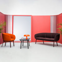 Modern seating in orange and dark brown, set against vibrant coral and pink backgrounds with sleek lines.