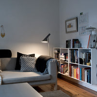 Neutral gray and black sofa with textured throw pillows, complemented by a white bookshelf and wooden flooring.