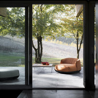 "Modern outdoor setting featuring an orange bean bag chair, gray patio table, and vibrant greenery."