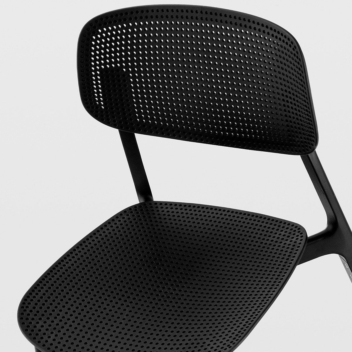 Black perforated chair with sleek, modern design and a minimalist pattern. Perfect for contemporary spaces.