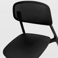 Black perforated chair with sleek, modern design and a minimalist pattern. Perfect for contemporary spaces.
