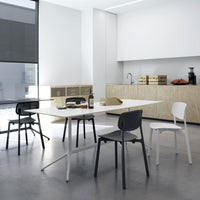 Modern dining room featuring white table, black and white chairs, and light wood accents in a minimalist design.