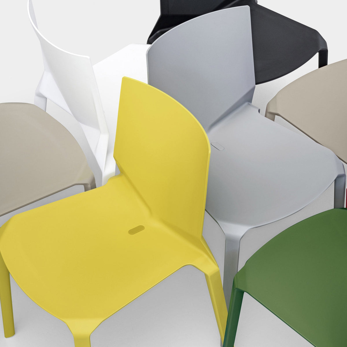 Colorful chairs in yellow, gray, white, green, tan, and black with sleek, modern designs and smooth finishes.