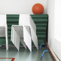 Stacked white chairs against green mats and a vibrant orange ball, creating a modern, minimalist color palette.