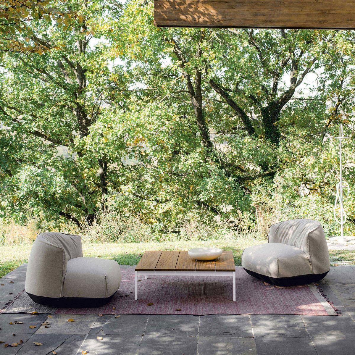 Beige and black bean bag chairs on a soft red and white patterned rug with natural greenery in the background.