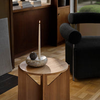 Elegant wooden side table with a smooth finish, complemented by neutral tones and soft textures in a cozy interior setting.