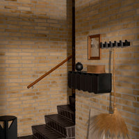 "Elegant black storage unit against warm textured brick wall, complemented by wooden accents and earthy tones."