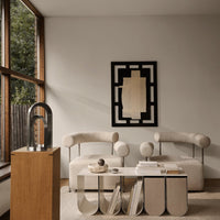 Neutral beige sofa with circular accents, geometric black and cream wall art, and a sleek wood pedestal table.