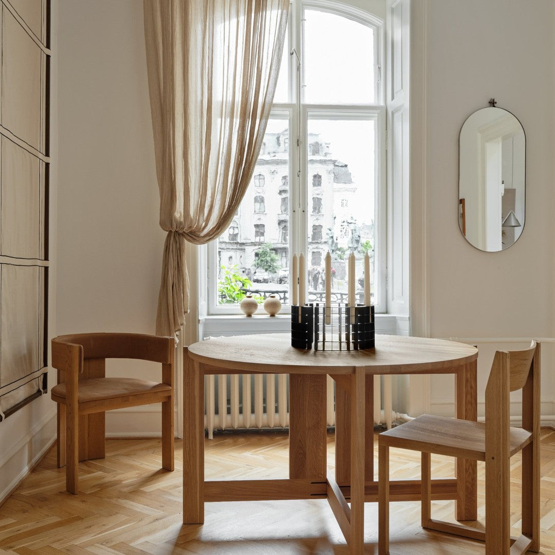 Light wood dining table with beige curtains and natural wood chairs, set against a light-toned room decor.