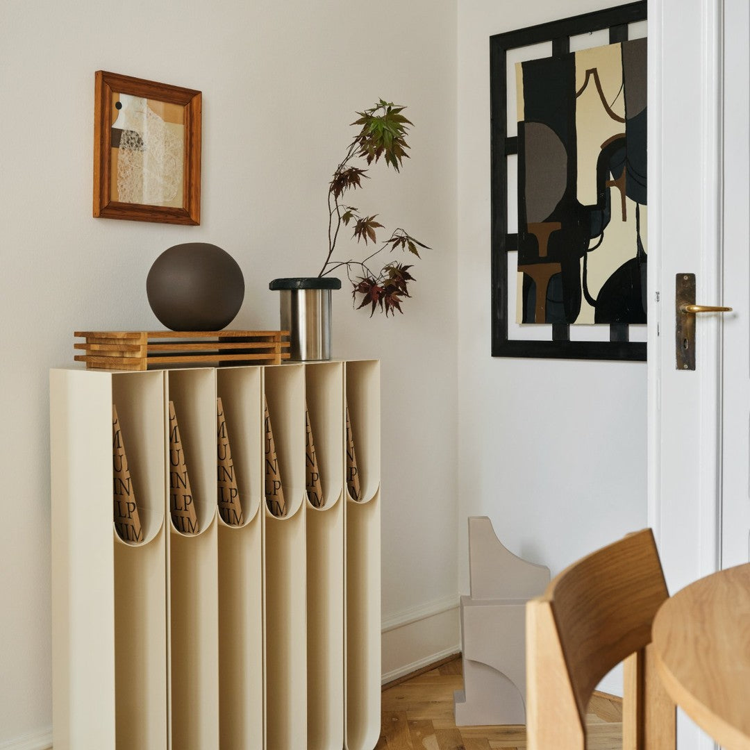 Beige storage unit with curved sections and artistic black and cream wall decor, complemented by natural wood tones.