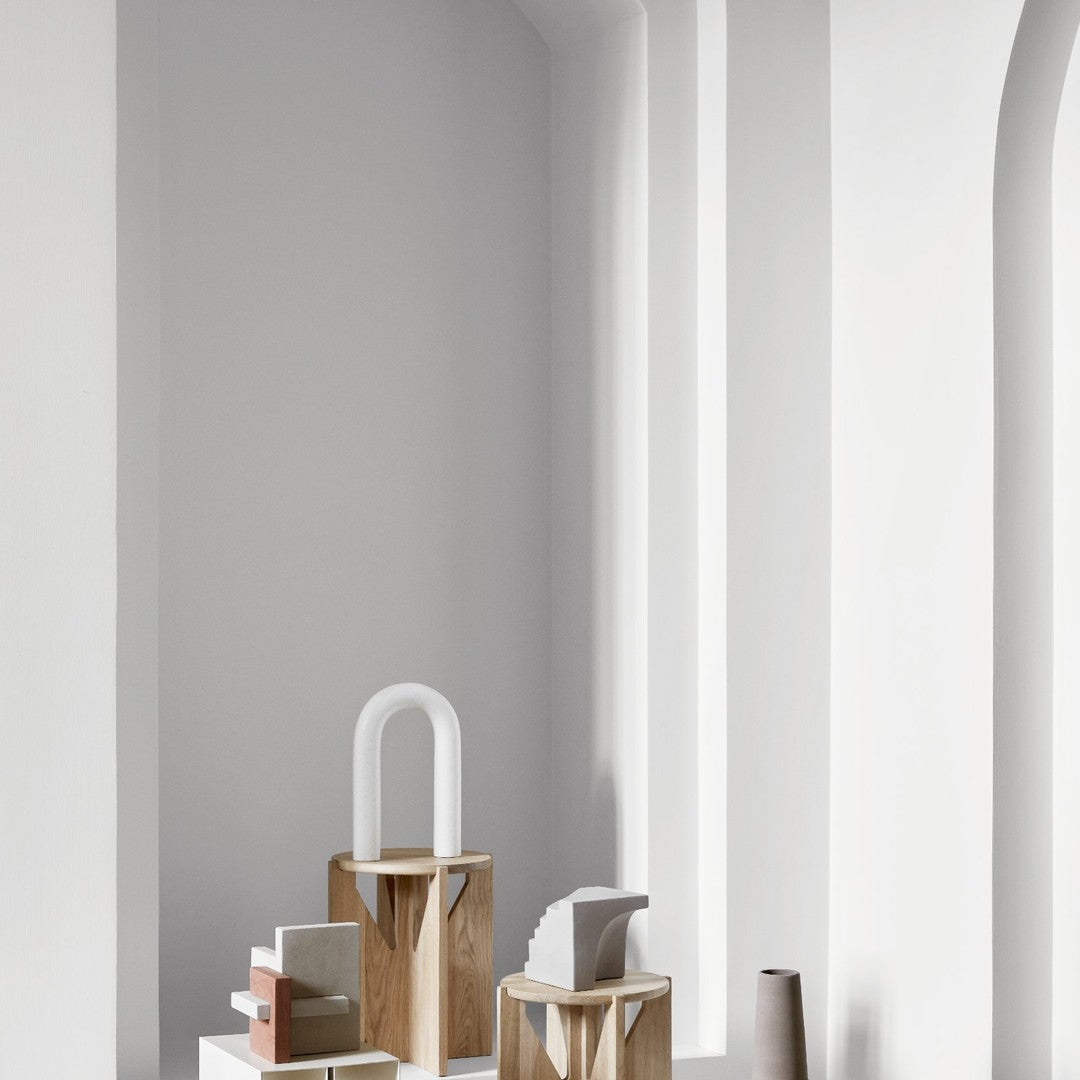 Minimalist decor showcasing neutral tones, wooden textures, and geometric shapes against a soft white backdrop.