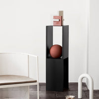 "Modern black pedestal with geometric accents; featuring earthy tones and a minimalist design."