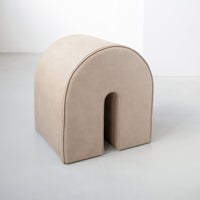 Beige arch-shaped ottoman with smooth, solid texture; minimalistic design for modern decor.