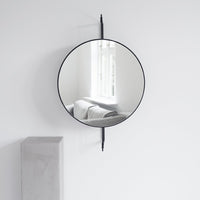 Round black-framed mirror reflecting soft gray sofa and white walls, enhancing minimalistic decor.