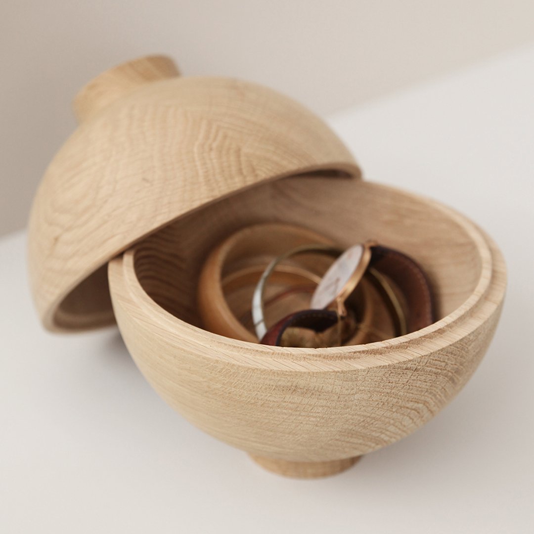 Natural wood grain bowl with a smooth beige finish, showcasing a collection of colorful patterned bangles inside.
