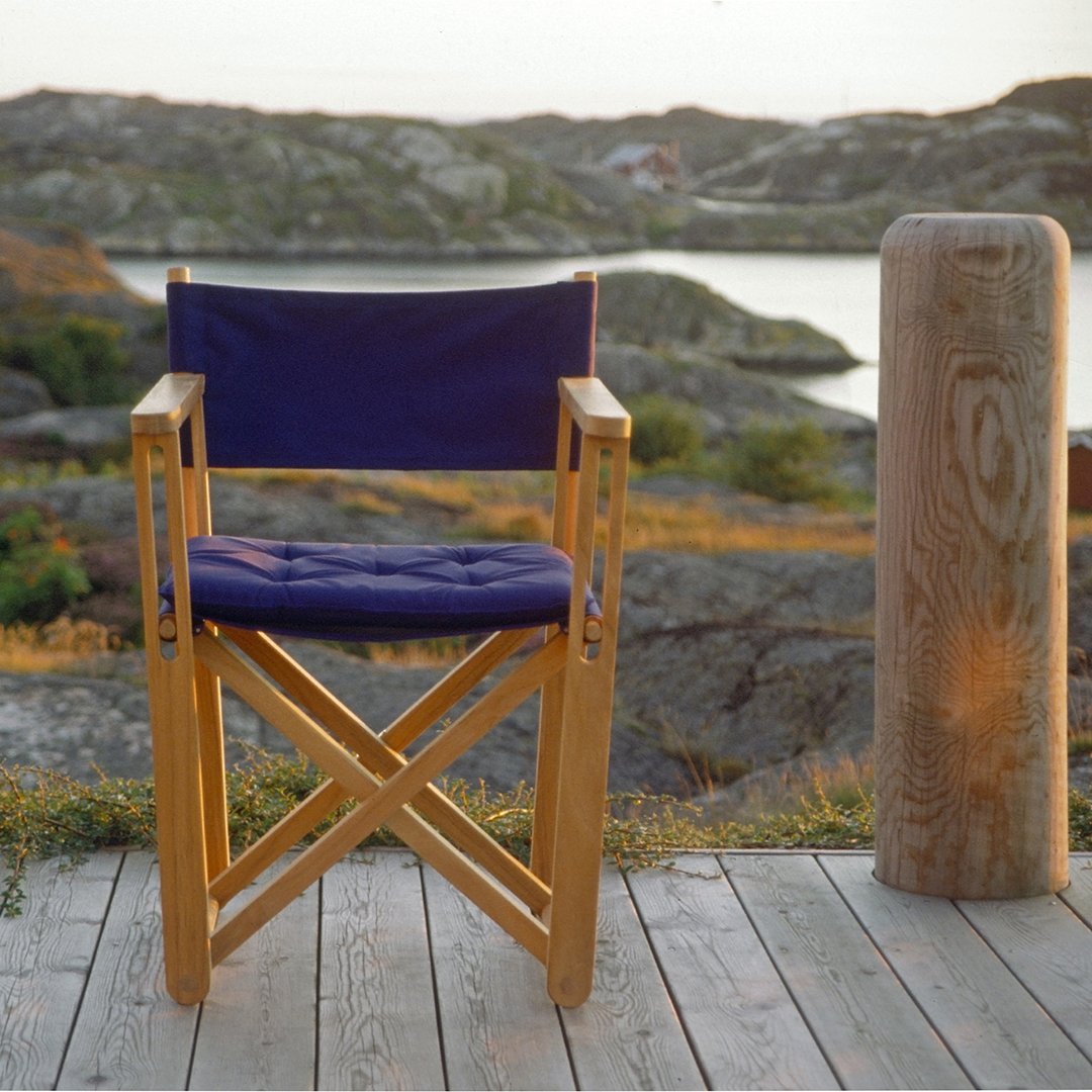 Navy blue canvas director's chair with natural wood frame, set against a scenic outdoor backdrop.
