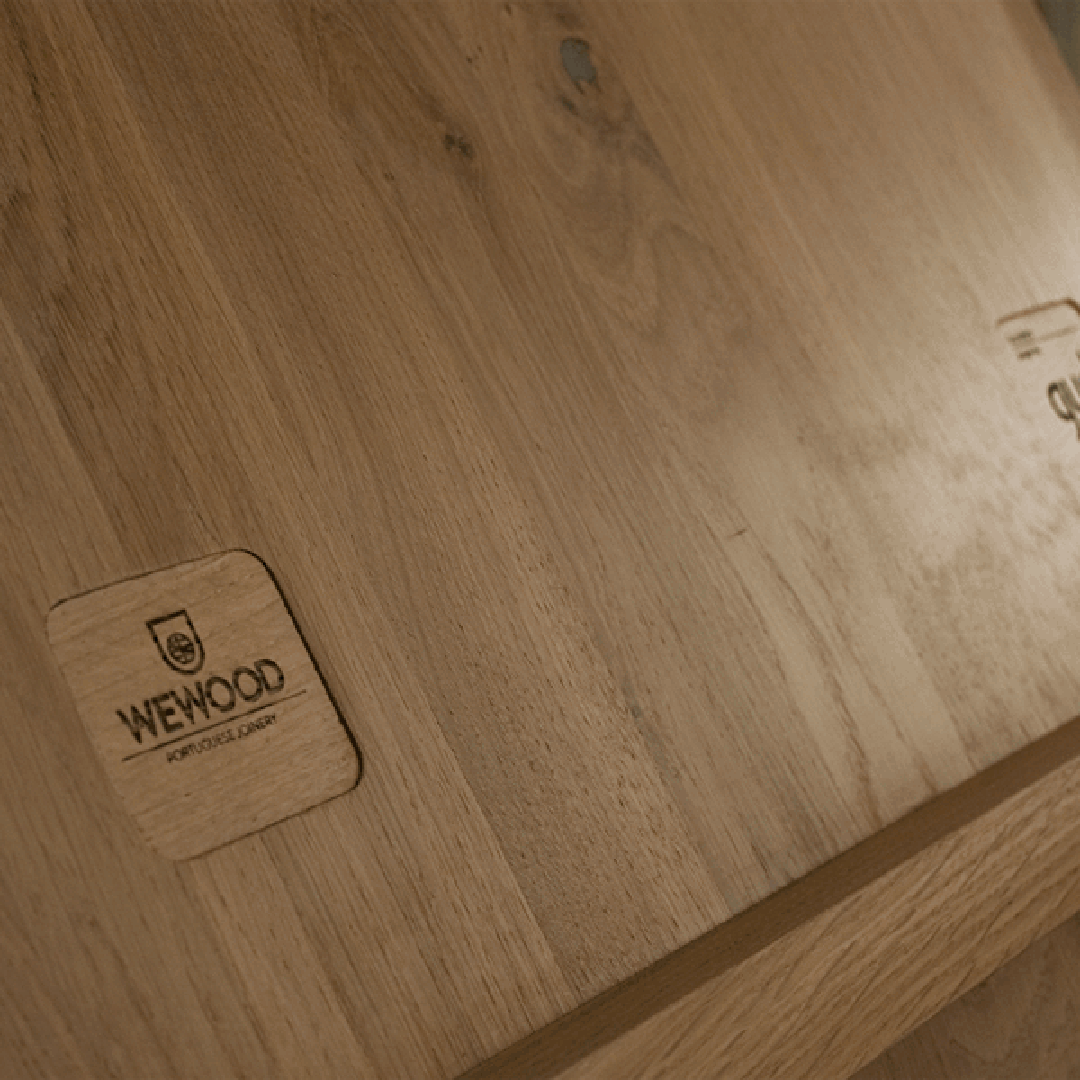 Light brown wooden surface with natural grain patterns and a smooth finish, featuring an engraved logo.