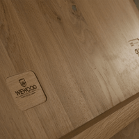 Light brown wooden surface with natural grain patterns and a smooth finish, featuring an engraved logo.