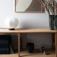 "Minimalist wood shelf with black and white decor, featuring soft curves and earthy tones for a modern aesthetic."