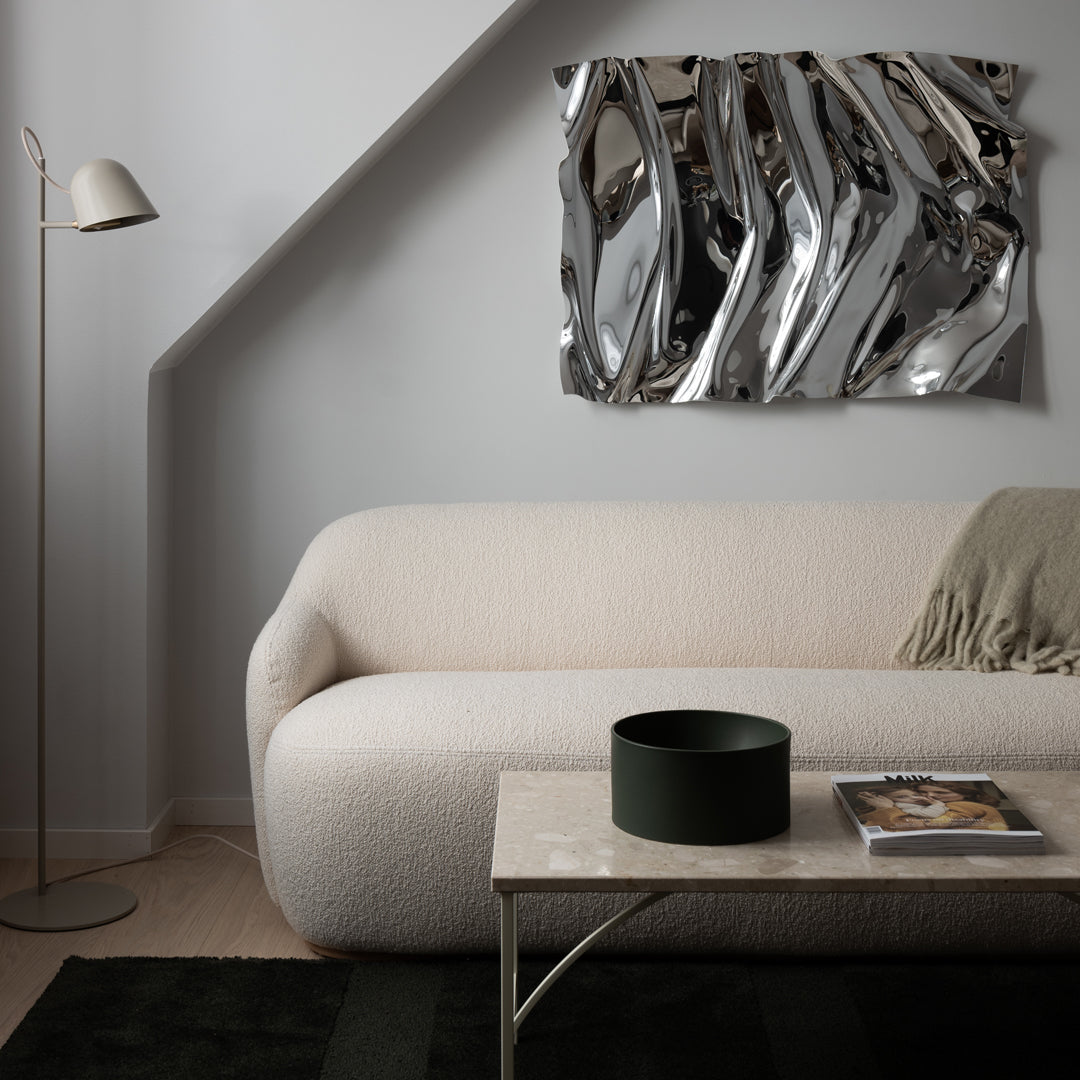 Abstract silver wall art with wavy patterns, complementing a neutral-toned living room decor.