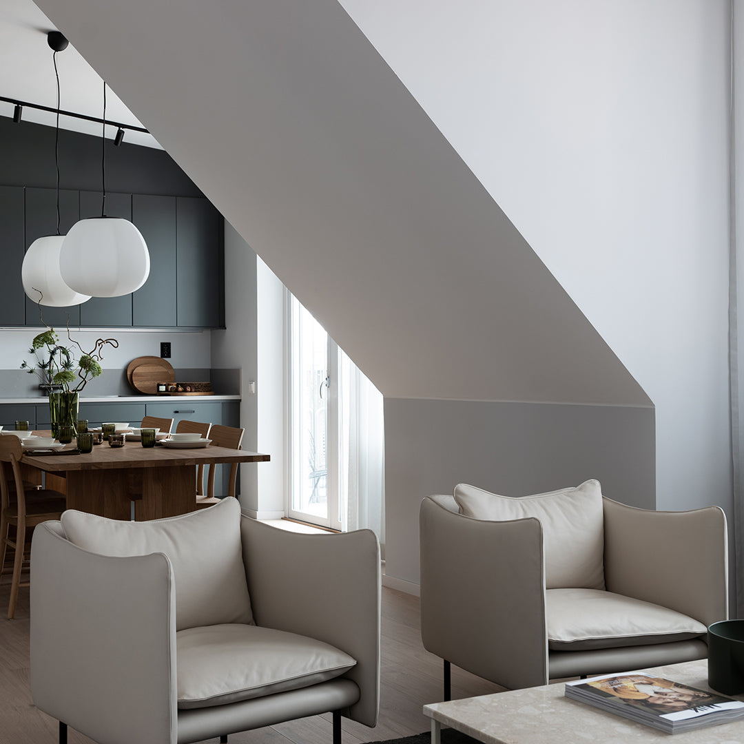 Cozy beige armchairs with minimalistic design in a modern, light-filled room featuring gray and white accents.