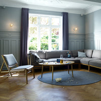 Cozy living room featuring a gray sofa, blue rug, natural wood accents, and purple curtains against a light blue wall.