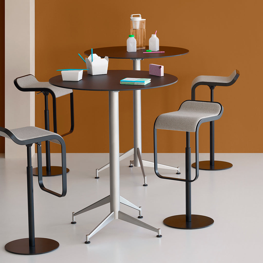 Modern round black and gray bar tables with sleek metal bases, set against a warm brown wall for a stylish look.