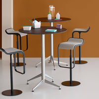Modern round black and gray bar tables with sleek metal bases, set against a warm brown wall for a stylish look.