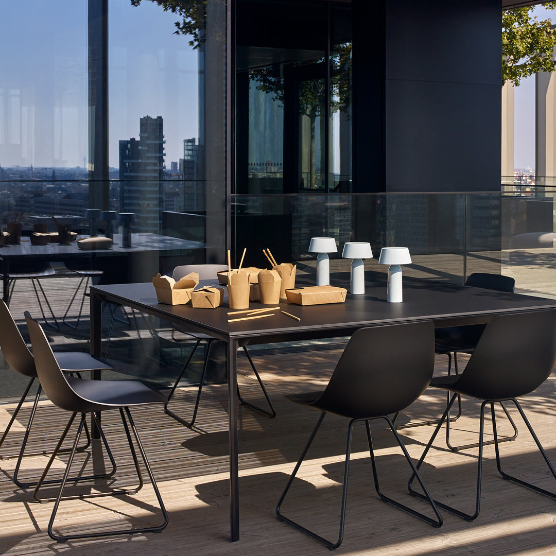 Black dining table with minimalist design, paired with sleek black chairs and soft white and wooden accents.