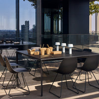 Black dining table with minimalist design, paired with sleek black chairs and soft white and wooden accents.