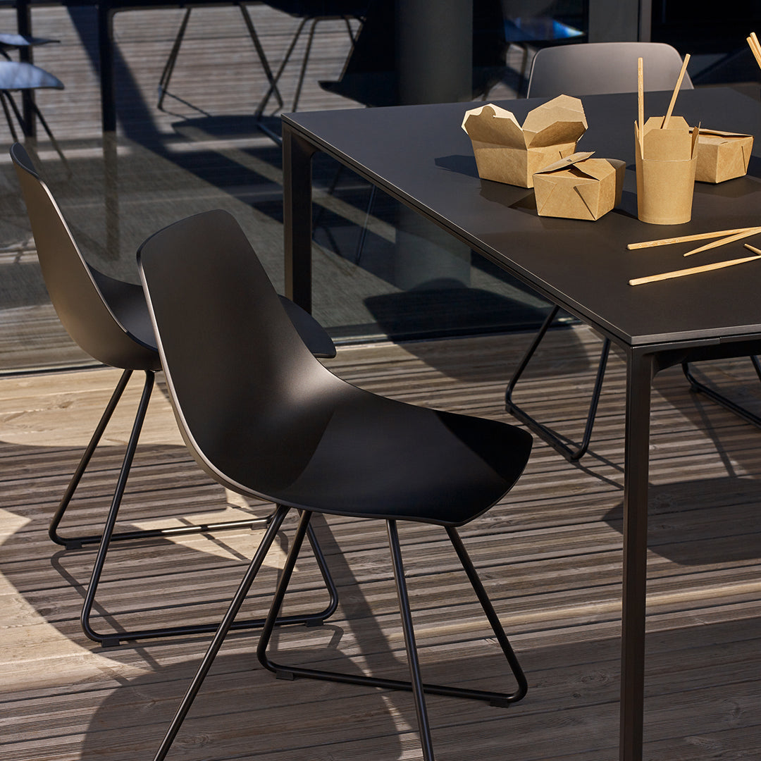 Black dining chairs with sleek curves, paired with a minimalist black table and subtle wooden floor patterns.