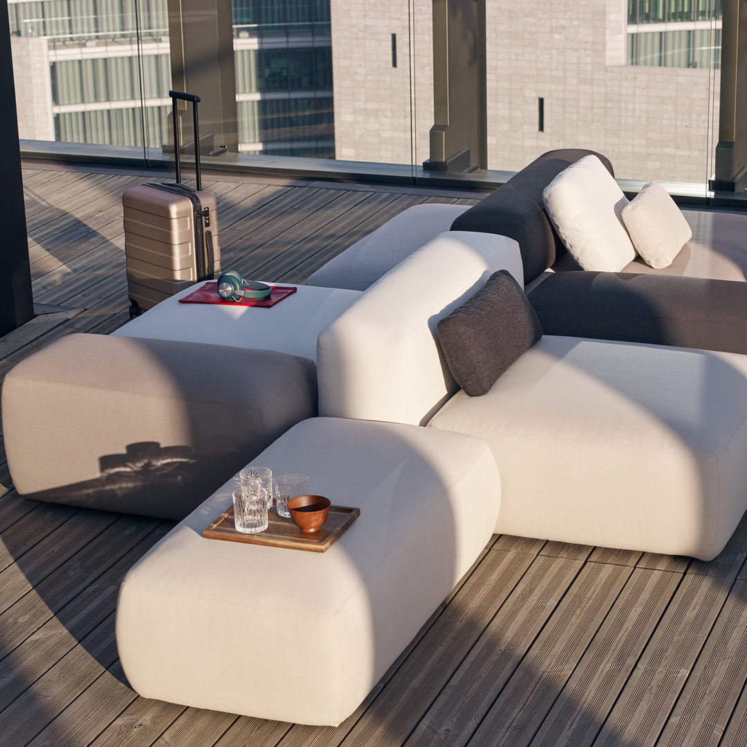 "Modern outdoor seating in light gray and dark gray with soft cushions, featuring sleek, rounded shapes."