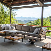 Modern outdoor sectional sofa in neutral grey with soft cushions, paired with a sleek black coffee table.