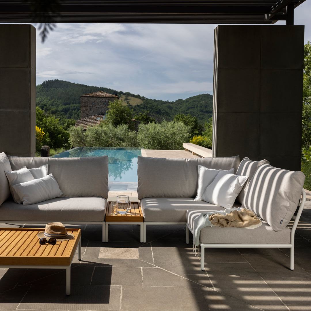 Stylish outdoor sectional with light gray cushions and striped accents, paired with a natural wood coffee table.