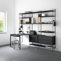 Minimalist black shelving unit with sleek lines and a modern desk, featuring a neutral gray floor and natural light.