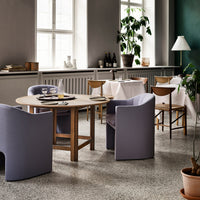 Stylish round dining table with light wood finish and muted gray chairs, complemented by earthy tones in the decor.
