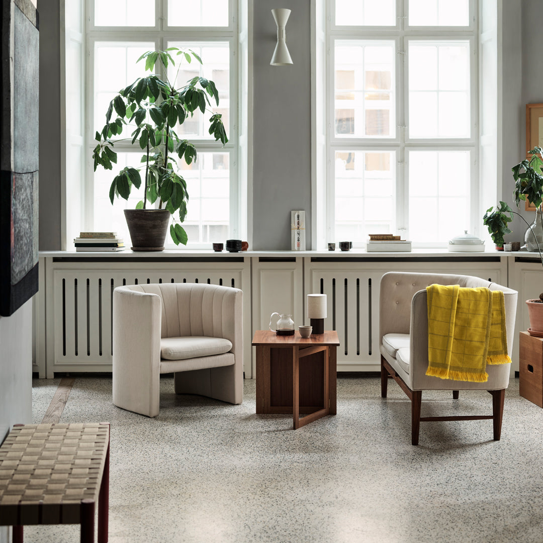 Modern living room featuring beige upholstered chairs, warm wooden accents, and vibrant yellow throw blanket.