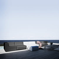 Modern outdoor sofa in sleek black and white with smooth, minimalist design against a serene blue sky backdrop.