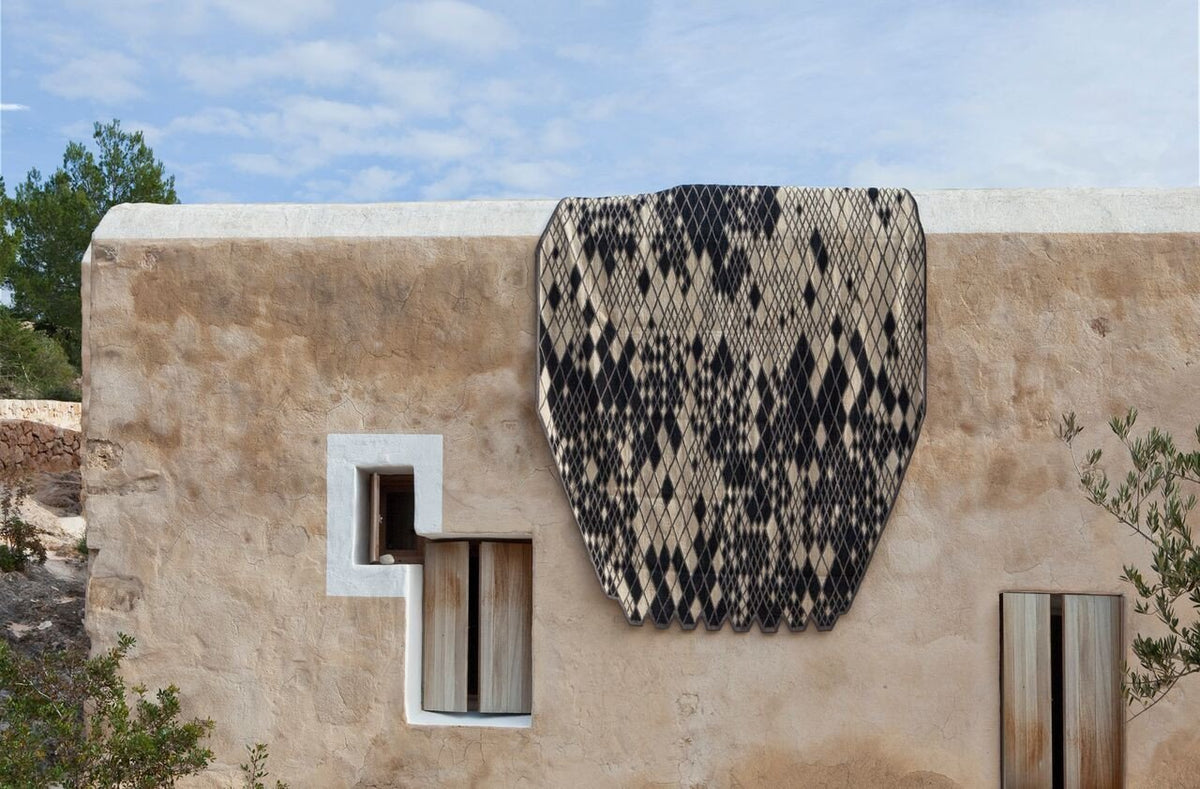 Black and cream patterned rug hung on a wall, showcasing a modern geometric design against a neutral background.