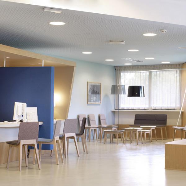 Office interior featuring blue and neutral tones with wooden accents, sleek furniture, and modern light fixtures.
