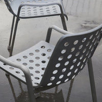 Gray perforated chairs with circular cutouts, designed for modern outdoor or indoor seating.