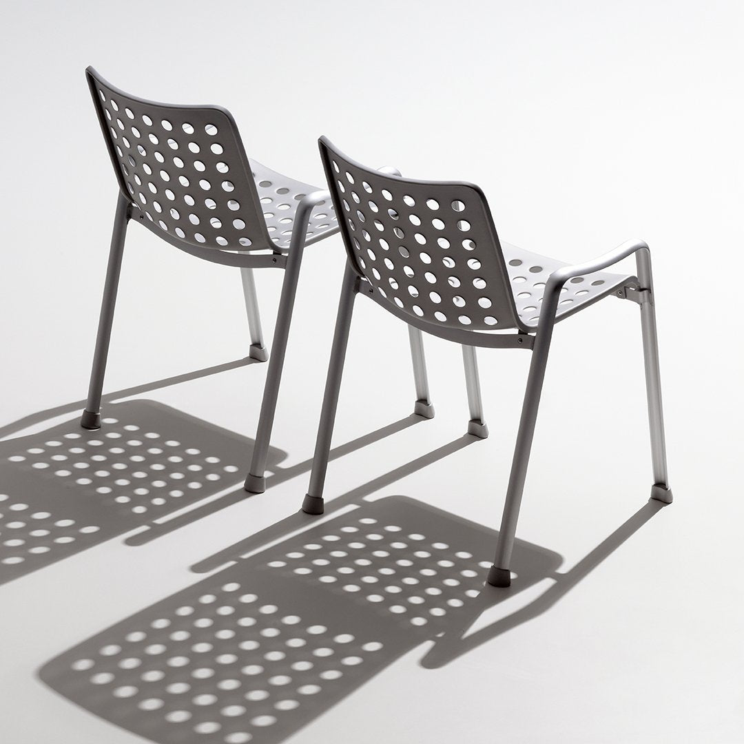 Gray chairs with polka dot patterns casting intricate shadows on a light background. Ideal for modern decor.