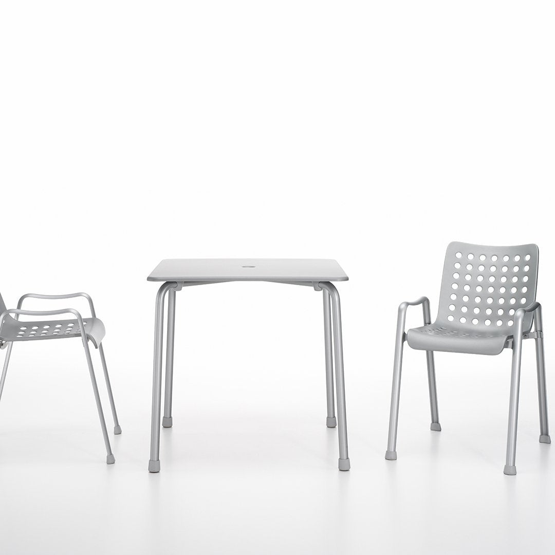 Gray outdoor table and perforated gray chairs on a white background, perfect for modern patio decor.