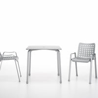 Gray outdoor table and perforated gray chairs on a white background, perfect for modern patio decor.