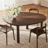 Elegant dark wood oval dining table with minimalist design, complemented by neutral-toned chairs and a textured rug.