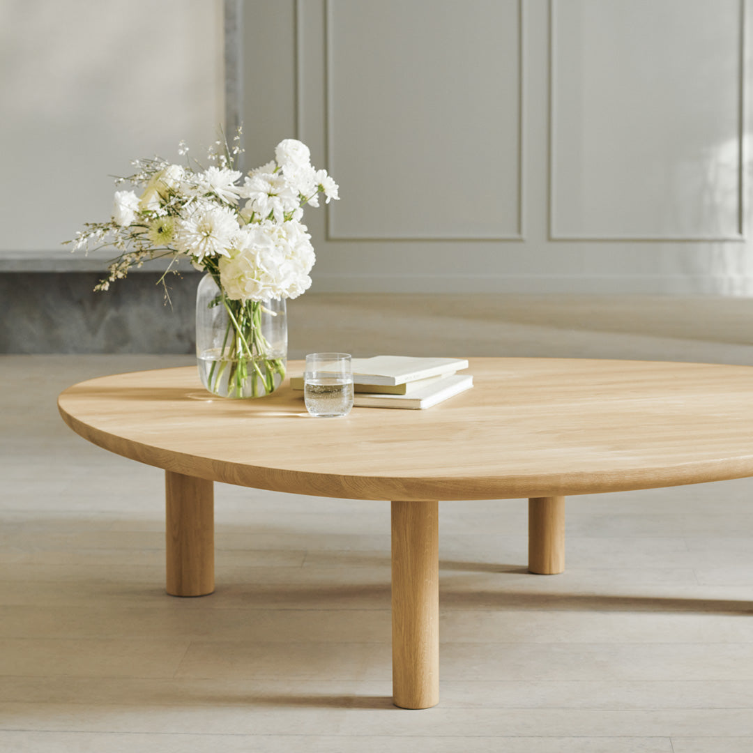 Natural wood coffee table with a smooth, light finish and simple round design, featuring a minimalist aesthetic.