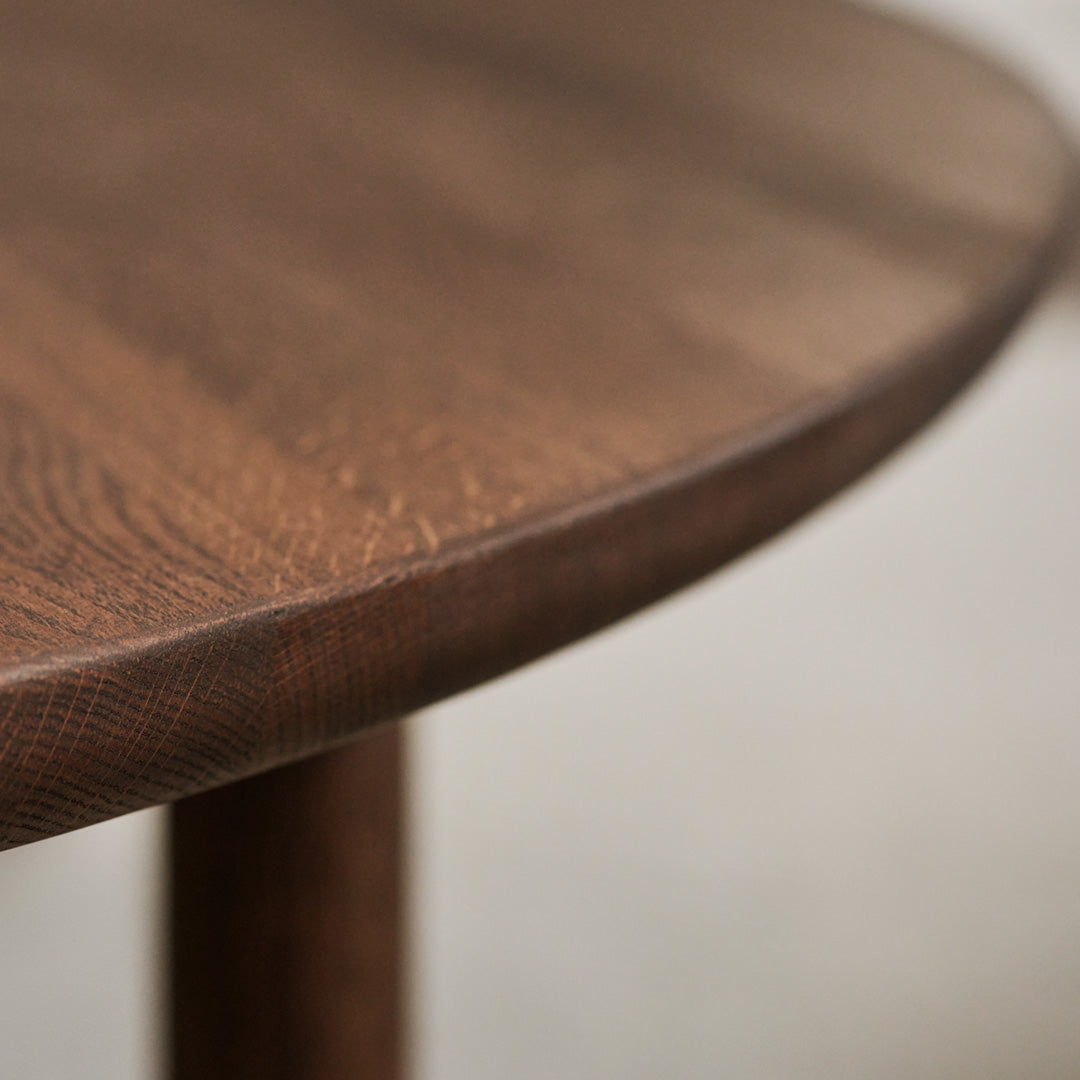 Close-up of a round brown wood tabletop with intricate grain patterns and smooth edges. Perfect for modern decor.