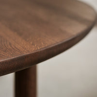 Close-up of a round brown wood tabletop with intricate grain patterns and smooth edges. Perfect for modern decor.