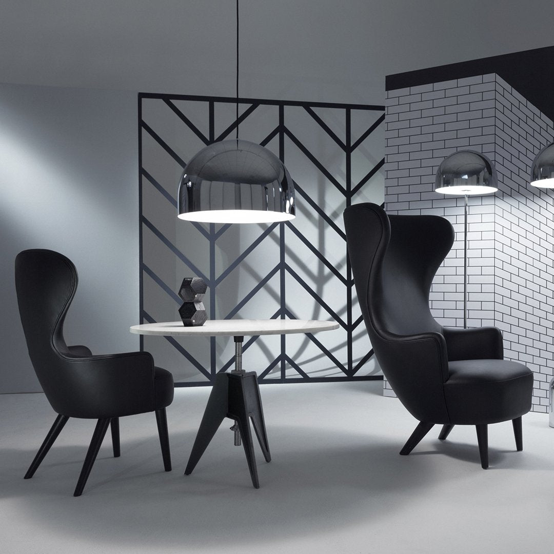 Black chairs with sleek contours and a contrasting white table, set against a geometric black-and-white background.